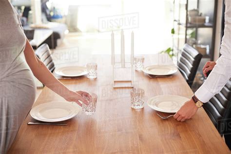 This larger knife is used to eat the main course, and can be replaced with a steak knife if required. Cropped shot of pregnant couple laying dining table ...