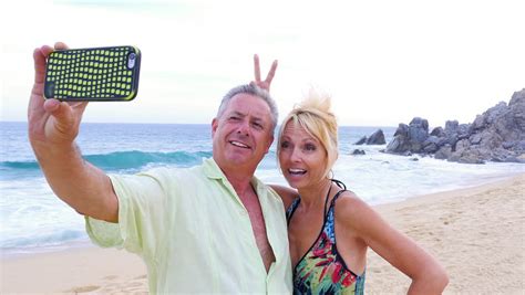Mature couple having outdoor fun. An Older Couple Having Fun And Taking Selfies On The Beach ...