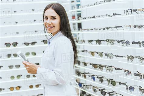 Attractive optician using digital tablet at work in ophthalmic shop - Stock Photo - Dissolve