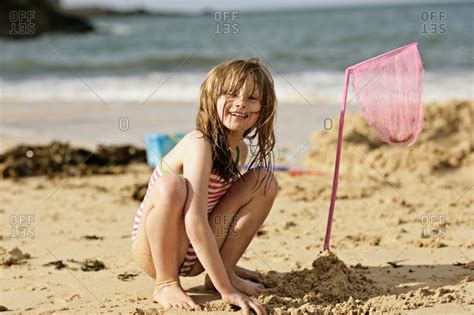 Teen fingering in the bath. Young girl squatting on a sandy beach stock photo - OFFSET