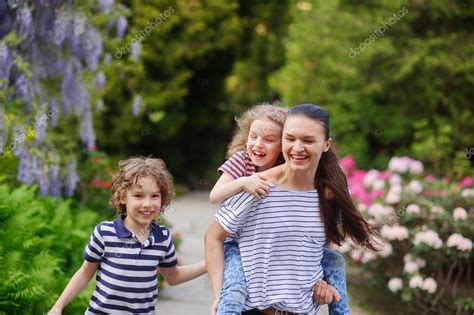 Mature jeune, french mature, french cougar. Jeune femme avec ses deux enfants marchant dans un jardin ...