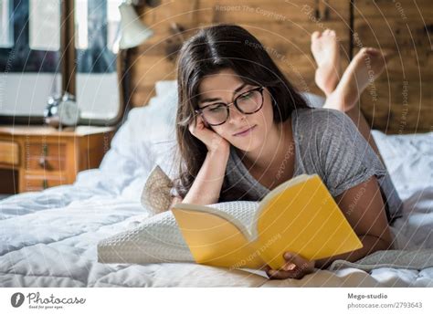 Porträt einer schönen jungen frau, die auf bett mit den beinen oben auf bett am schlafzimmer liegt. Junge nackte Frau, die zu Hause auf dem Bett liegt. - ein lizenzfreies Stock Foto von Photocase