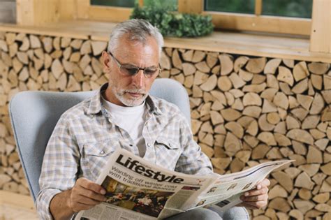 A vendre 6 chaises en chêne. Senior homme assis sur une chaise lisant un journal près ...