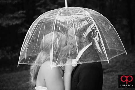 We love adventurous outdoor wedding photos with bridal couples holding an umbrella in a rain shower. Rain Wedding Photo Ideas - Rainy Day Wedding Photos