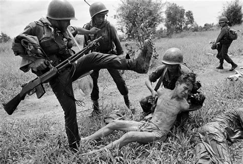 A South Vietnamese soldier kicks a suspected member of the 