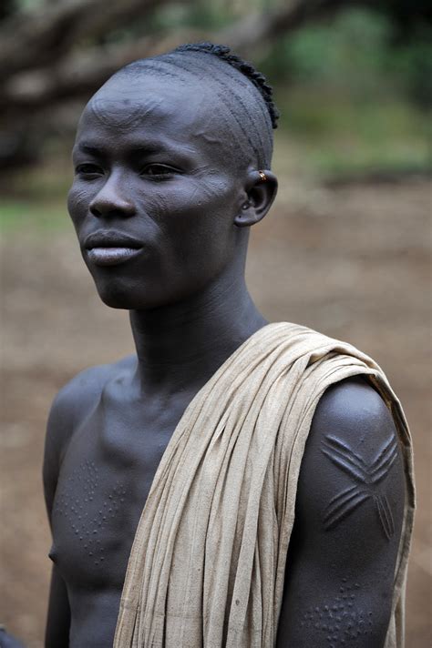 In the middle of a cold, cold night. Kachipo young boy with scarifications and typical hairdres ...