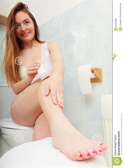 How to clean vagina hair? Woman Shaving Legs With Depilator In Bathroom Stock Photo ...