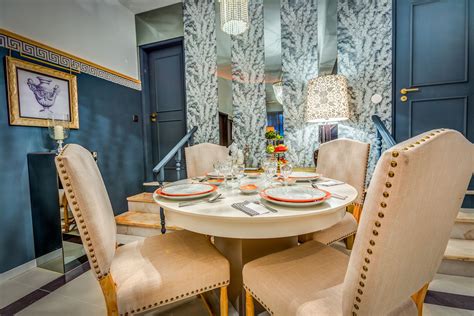 Gray and pink dining room features a vaulted ceiling accented with a brass sputnik chandelier, arteriors zanadoo pendant, illuminating an oval dining table lined with pink velvet dining chairs placed atop an orange and pink rug placed in front of bay windows dressed in dark gray curtains. Miguel da Cunha | Sala de Jantar | Dining Room | Plates | Grey | Beige | Orange | Dining Table ...