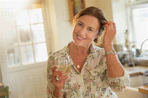 Portrait smiling mature woman drinking white wine in kitchen - Stock ...