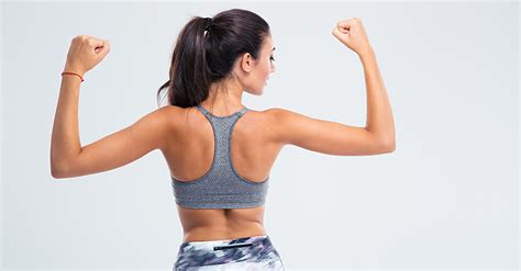 Young brunette woman flexing back and hand muscles on gym machine (stock footage). Sculpting Long, Lean and Lovely Shoulders - Women Fitness